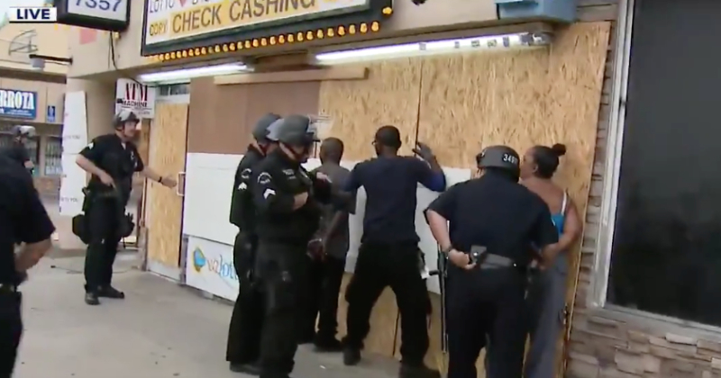 African American business owner handcuffed while the police officers are confused. 