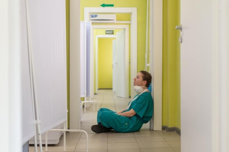 medical health worker sitting on the floor in hospital corridor