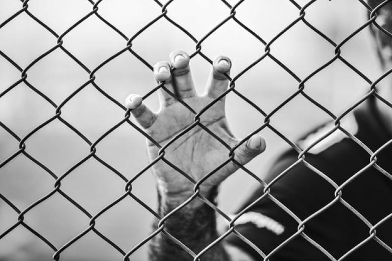 man holding chainlink fence with hand