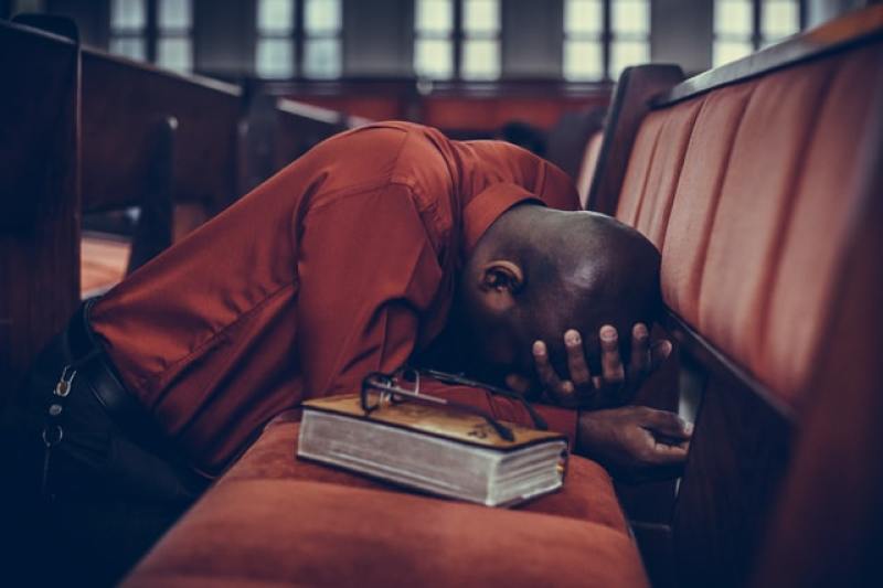 man in church kneeling in prayer