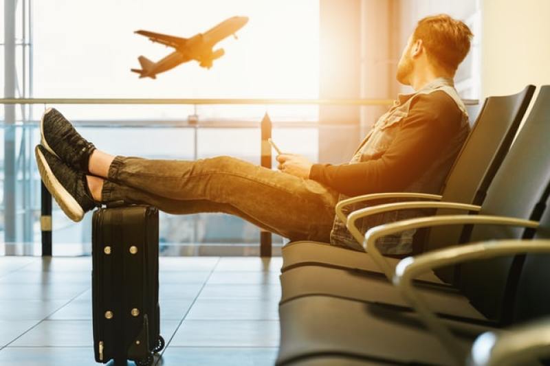man sits on gang chair inside the airport, left by his flight