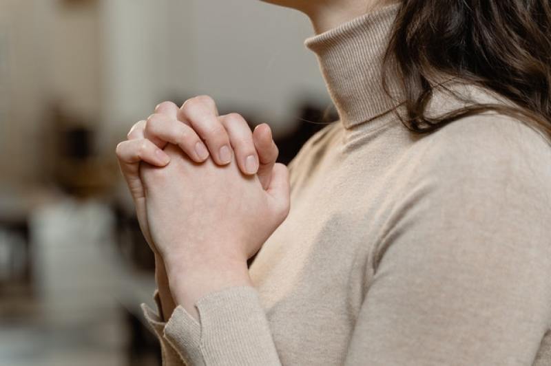 woman praying with her hands clasped