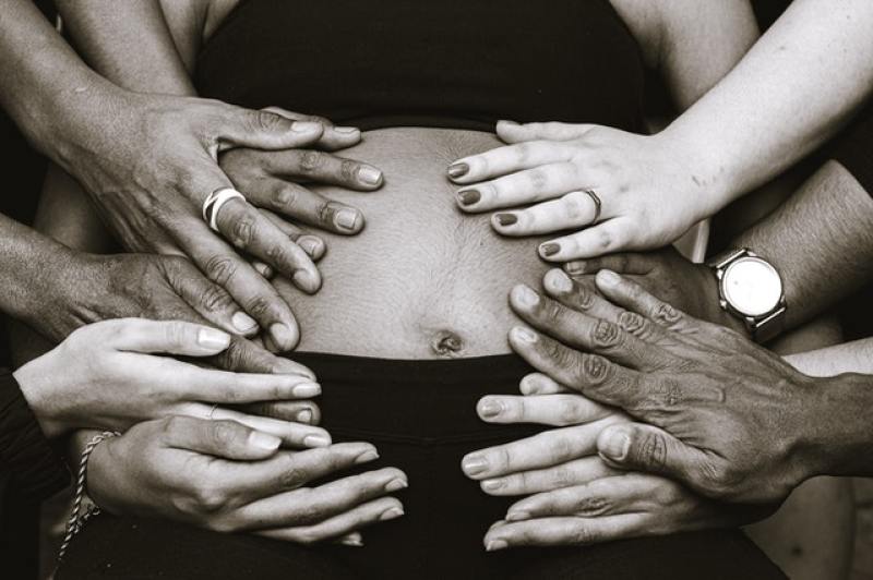 pregnant mom with many hands holding her tummy