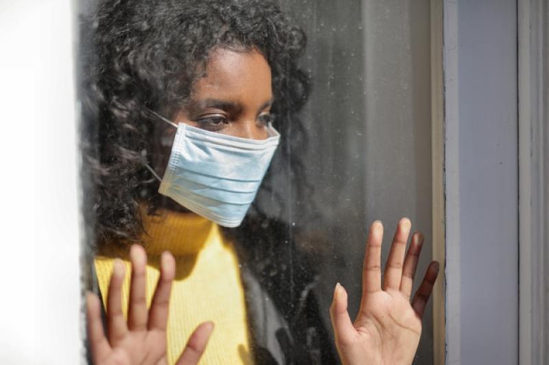 woman wearing mask inside room behind glass window