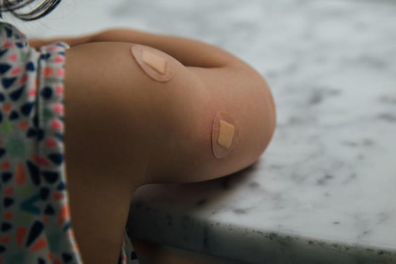 child with multiple injection marks covered in band-aid