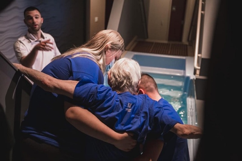 86-year-old Joy Stamey receiving help to get baptized in water