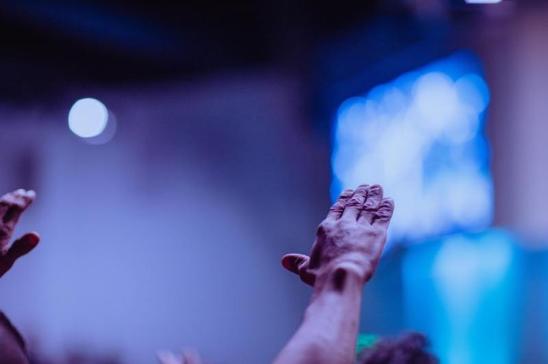 wrinkled hands raised in worship in church